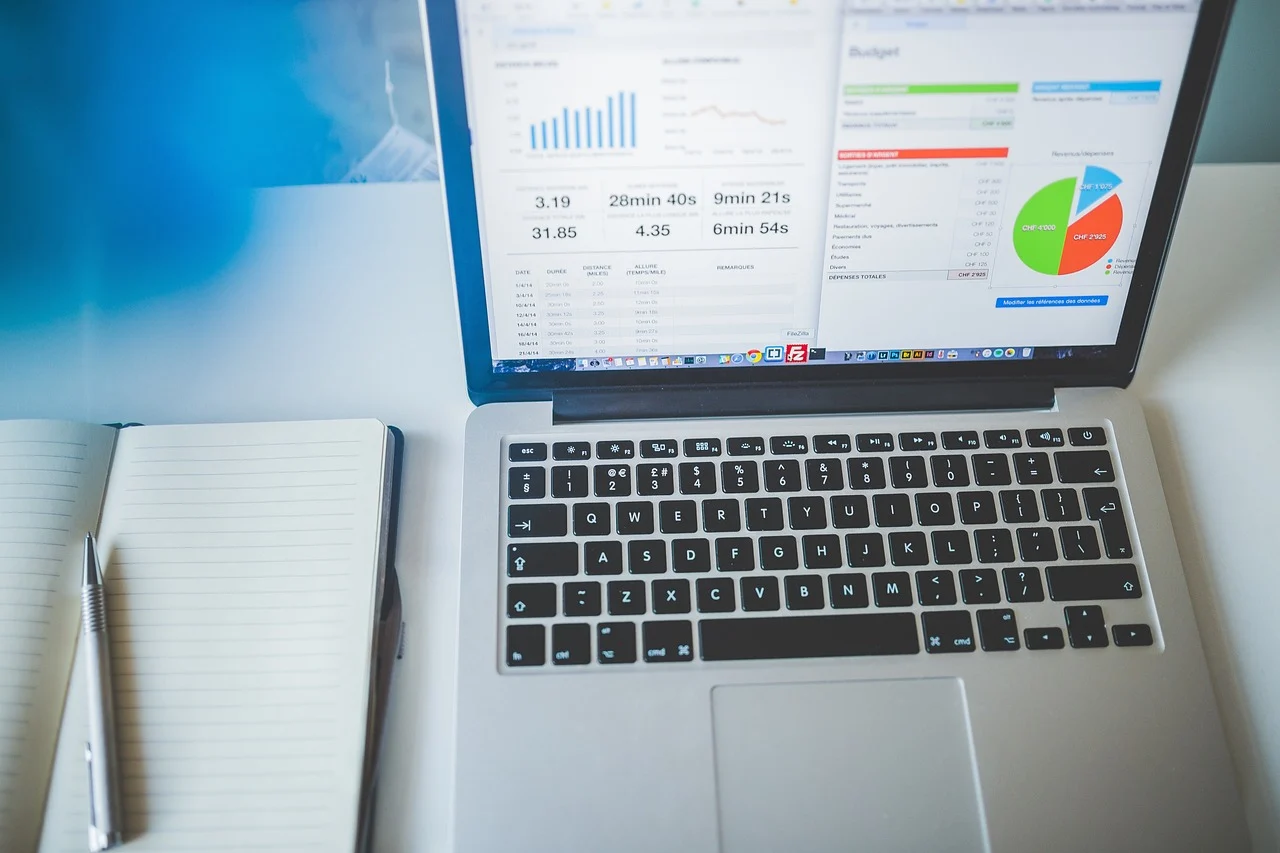 A laptop on a desk showing a Google Search Console dashboard with keyword data visible